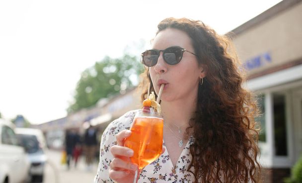 Woman enjoying day in outdoor cafe. Woman drinking iced summer cocktail  - Photo, Image