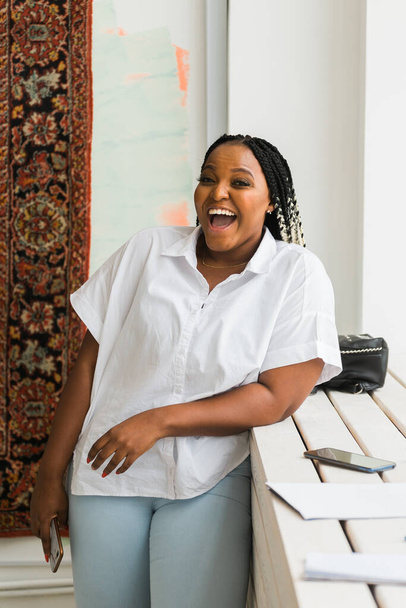 Portrait of beautiful african american woman laughing and looking at camera. Female with a big grin. Carefree and cheerful lady having fun at home in morning - Foto, Imagen