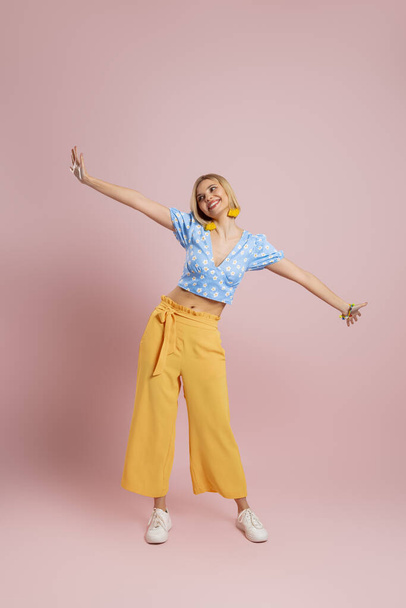 Full length of fashionable young woman dancing and smiling against color background - Fotografie, Obrázek
