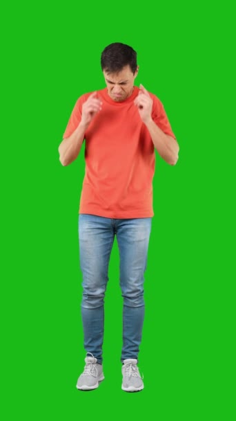 Πλήρες σώμα του ενοχλημένου ανδρικού μοντέλου που καλύπτει τα αυτιά από αηδιαστικό θόρυβο και κάνει δυσαρεστημένο πρόσωπο σε πράσινο φόντο - Πλάνα, βίντεο
