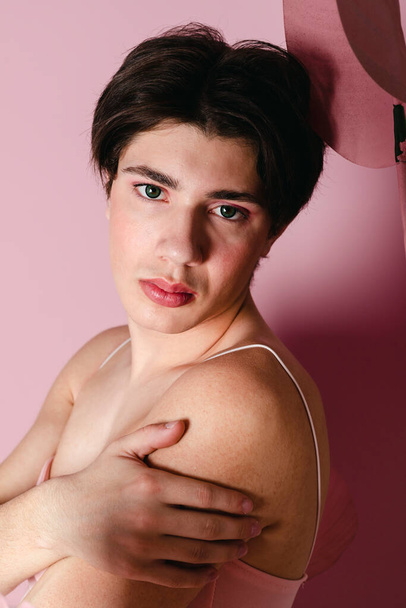 Detailní záběr Portrét něžného gaye v růžových šatech. Okouzlující homosexuální mladík s make-upem pózující v dívčím kostýmu. snímek hlavy. - Fotografie, Obrázek