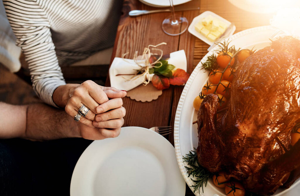 感謝する理由を見つけなさい。感謝祭のダイニングテーブルで恵みと言っている認識できない家族の高角度ショット - 写真・画像
