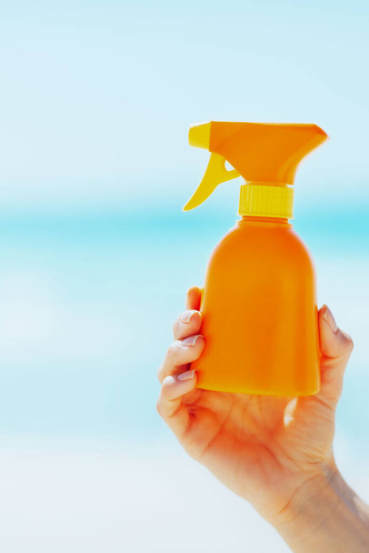 Closeup on bottle of sun screen creme in hand of woman - 写真・画像