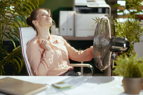 Sustainable workplace. relaxed modern small business owner woman at work with electric fan. - Фото, изображение