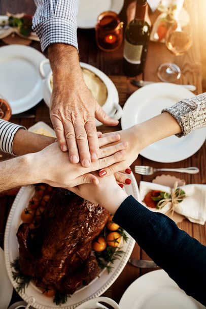 Jedzenie, łączenie rąk i ludzi razem przy stole, aby świętować święta, Boże Narodzenie lub dziękczynienie. Powyżej rodziny lub grupy przyjaciół ze stosem rąk dla wdzięczności, kurczaka lub indyka na obiad lub kolację. - Zdjęcie, obraz