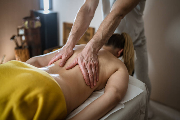 Mujer desconocida mintiendo mientras tienen masaje de espalda por terapeuta caucásico masculino en tratamientos de spa de belleza salón cuidado de la salud concepto de relajación espacio de copia - Foto, Imagen