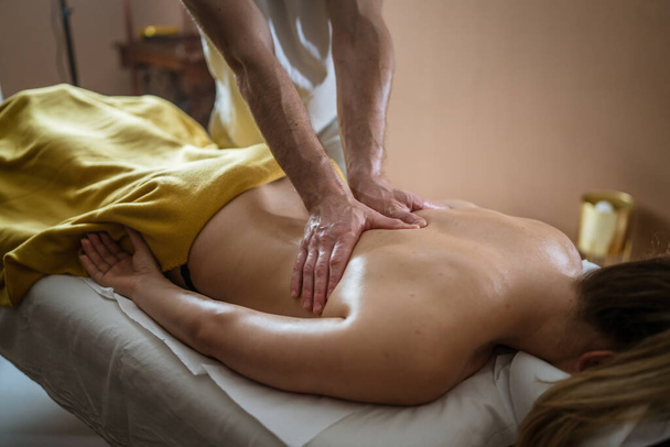 Mujer desconocida mintiendo mientras tienen masaje de espalda por terapeuta caucásico masculino en tratamientos de spa de belleza salón cuidado de la salud concepto de relajación espacio de copia - Foto, imagen