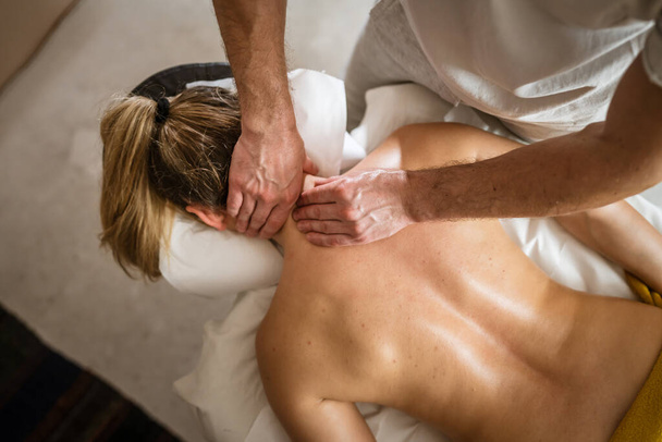 Nieznana kobieta leżąca podczas masażu szyi przez męskiego kaukaskiego terapeuty w gabinecie zabiegów kosmetycznych zabiegi spa salon opieki zdrowotnej relaks koncepcja przestrzeń kopia - Zdjęcie, obraz