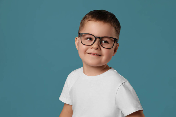 Cute little boy in glasses on light blue background - Φωτογραφία, εικόνα