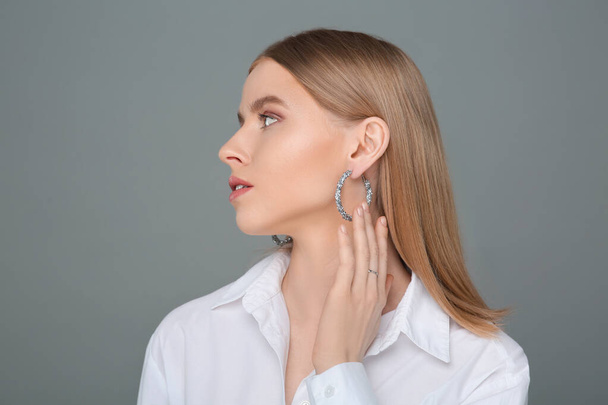 Beautiful young woman with elegant earrings on gray background, space for text - Φωτογραφία, εικόνα