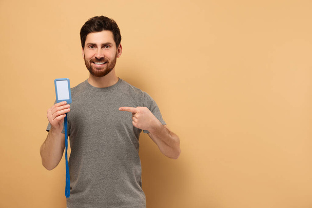 Happy man showing VIP pass badge on beige background, space for text - Φωτογραφία, εικόνα