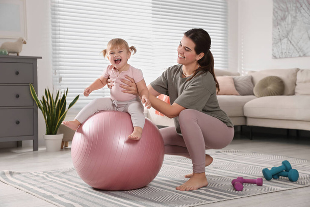 Mother doing exercise with her daughter on fitball at home - Fotografie, Obrázek