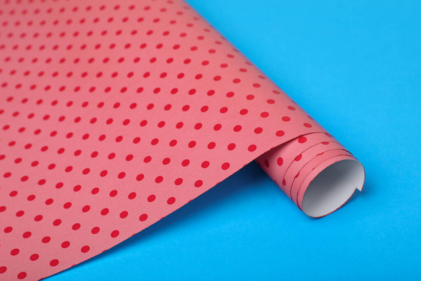 Roll of polka dot wrapping paper on light blue background, closeup - Foto, Imagem