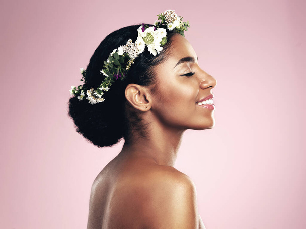 Woman, smile and beauty of flower crown in studio, pink background and spring aesthetic. Face of happy african model, natural skincare and floral hair wreath for vegan cosmetics, makeup and shine. - Foto, imagen