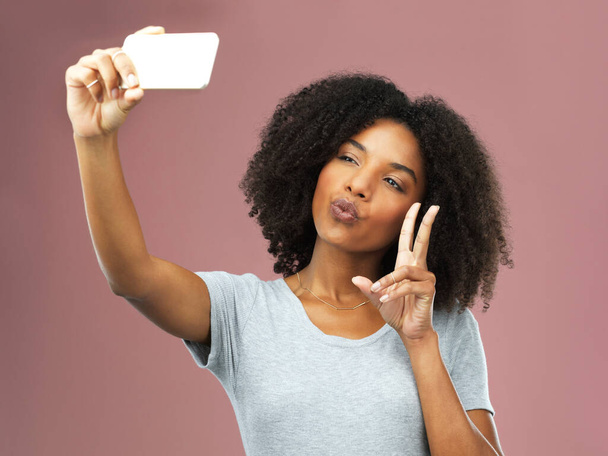 Het is pas een selfie als je pucker en pruilt. Studio shot van een aantrekkelijke jonge vrouw het nemen van een selfie tegen een roze achtergrond - Foto, afbeelding