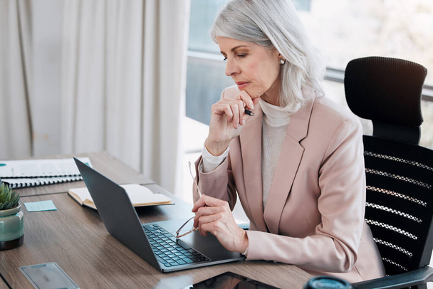 Este e-mail é interessante. uma mulher de negócios madura sentada sozinha no escritório e olhando contemplativa ao usar seu laptop - Foto, Imagem