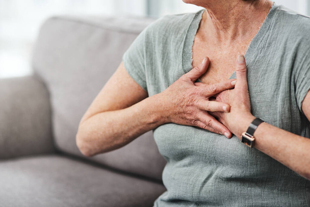 Heart attack, chest pain and sick senior woman with asthma in her home living room or couch with an emergency. Crisis, medical and elderly person with discomfort due to illness or breathing problem. - Fotó, kép