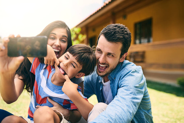 Happy family, smile and silly face for selfie, funny photo or profile picture in social media vlog outside home. Mother, father and child smiling with goofy facial expression for fun memory together. - Photo, image