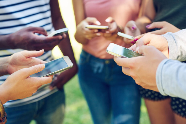 Hands, phone and circle with texting, friends and student on social media app, web or internet in park. Men, women and smartphone in group with cloud computing, online gaming and outdoor together. - Foto, Bild
