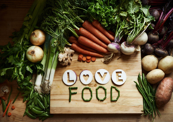 Listo para cocinar. Bodegón de una variedad de verduras en una tabla de cortar con el mensaje de amor y comida - Foto, imagen