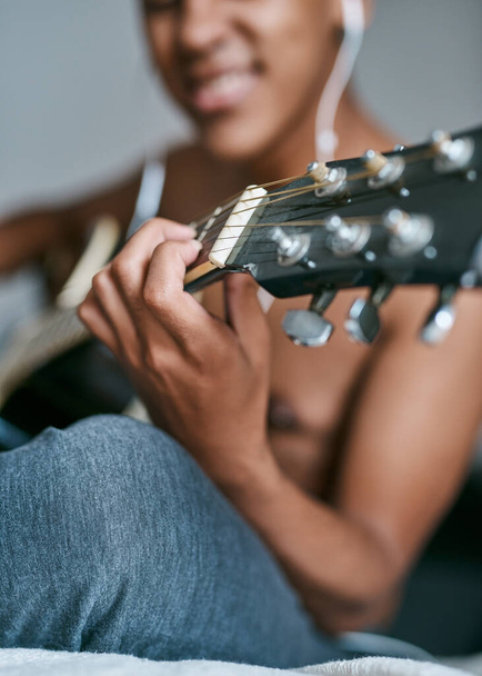 Ponte en sintonía con la buena música. un joven que usa auriculares mientras toca la guitarra en casa - Foto, Imagen
