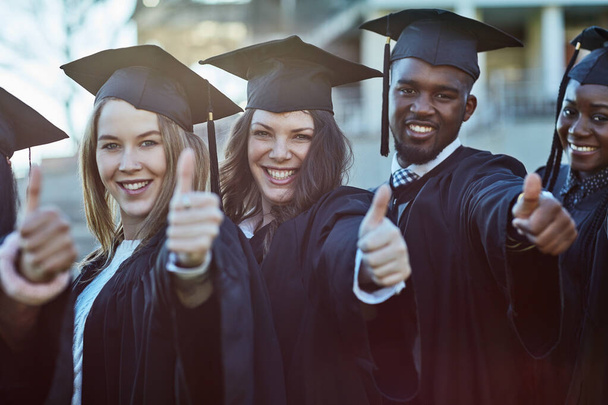 If we did it then so can you. Portrait of a group of students showing thumbs up on graduation day - Foto, afbeelding