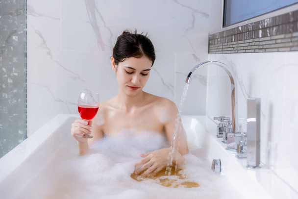 Relaxed woman laying in bathtub. enjoyment concept. woman in soap bubbles and having fun while lying in bathtub full of foam at home. Beautiful woman relax enjoy in bathtub in bathroom. - Foto, imagen