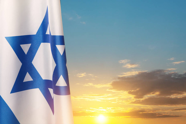 Israel flag with a star of David over cloudy sky background on sunset. Patriotic concept about Israel with national state symbols. Banner with place for text. - Foto, Bild