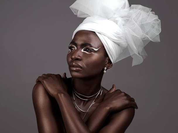Az afrikai szépség szimbóluma. Stúdió lövés egy vonzó fiatal nő pózol a hagyományos afrikai öltözékben, szürke háttér - Fotó, kép