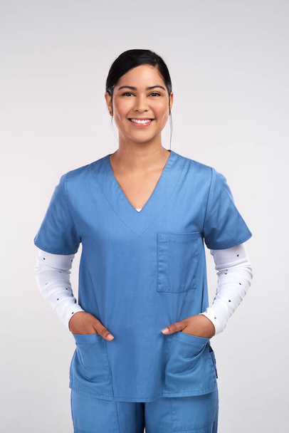 Where its always a matter of life or death. Portrait of a young doctor standing with her hands tucked into her scrubs against a white background - Fotoğraf, Görsel