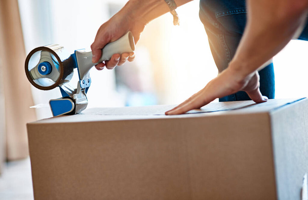 Closeup, cardboard and man with tape, box and move with items, home and shipping parcel. Zoom, male person and guy with tool, seal package or hands with products, closing or relocation with property. - Foto, imagen