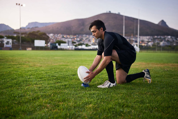 On my way to greatness. Full length shot of a handsome young sportsman crouching alone during rugby practice in a sports club - Fotó, kép