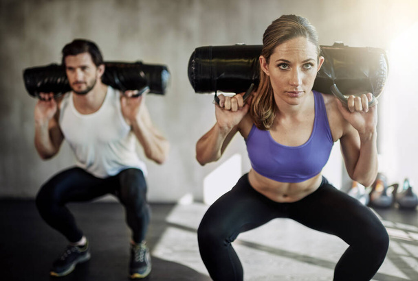Make yourself unstoppable. two young people working out in the gym using weighted bags - Fotoğraf, Görsel