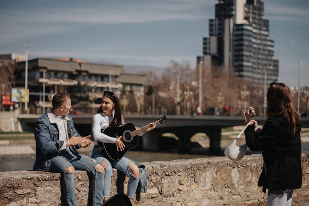 Zenész pár gitározik és énekel, miközben a barátjuk fotózza őket. - Fotó, kép