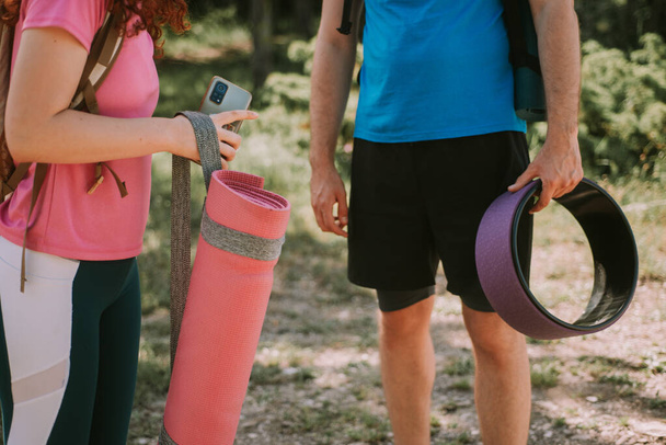 Крупним планом партнери з йоги тримають йогурт і йогу колесо, стоячи в лісі
 - Фото, зображення
