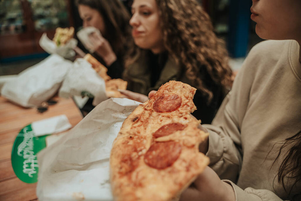 Girl holding a slice of pizza. Close up shot - Photo, image