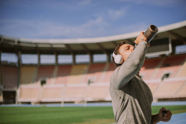Un maschio disidratato sta bevendo acqua dopo aver corso per lo stadio tutto il giorno - Foto, immagini