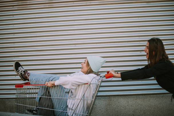 Two bautiful best friends having fun with a market cart - Фото, зображення