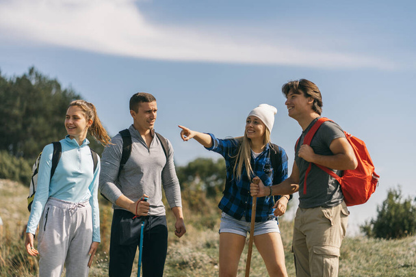 Blondýny dívka ukazuje něco svým přátelům, zatímco stojí na hoře - Fotografie, Obrázek