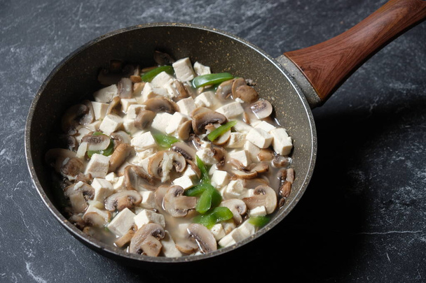 Tumis Tahu Jamur Kancing Paprika, tofu salteado, champiñones y pimientos verdes en una sartén de mármol. Comida indonesia. menú vegano. alimentos saludables. - Foto, imagen