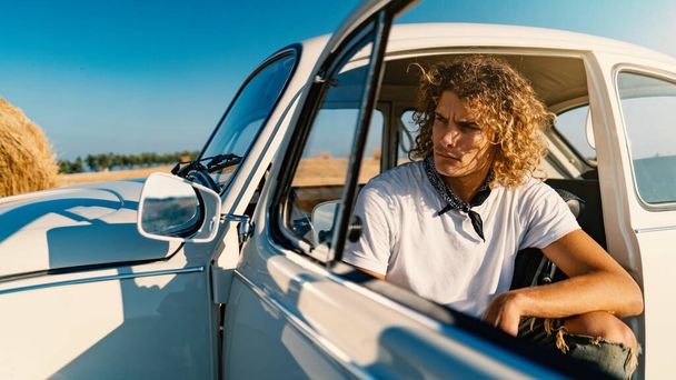 Young casual curly man portrait with vintage car. Lifestyle in a sunny day. - Φωτογραφία, εικόνα