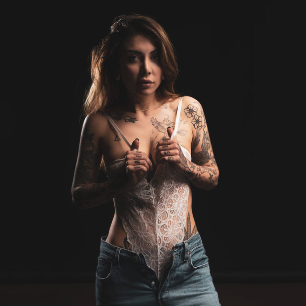Sexy woman studio portrait with white lingerie and tattoos against dark background. - Foto, afbeelding
