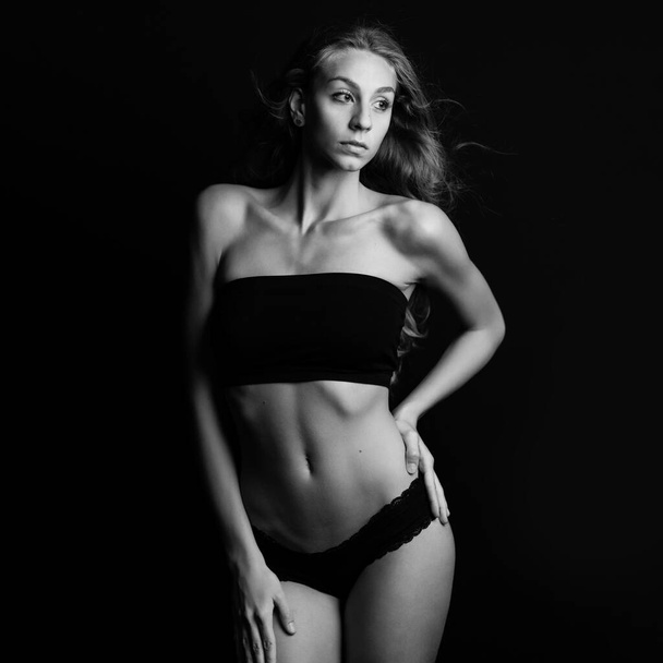 Sexy blonde woman portrait with black underwear isolated on dark background. Studio portrait. Black and white. - Photo, Image