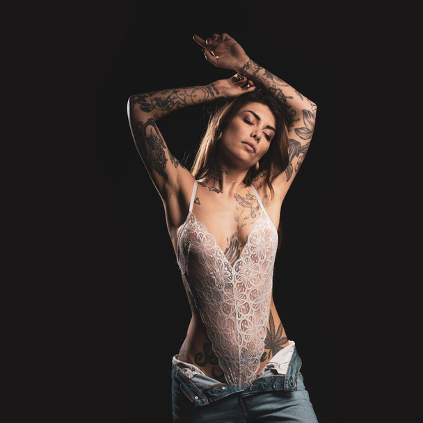 Sexy woman studio portrait with white lingerie and tattoos against dark background. - 写真・画像
