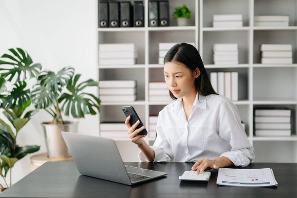Asian businesswoman working in the office with phone and laptop - Foto, Bild