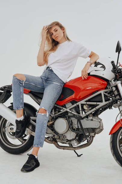 Estúdio tiro de isolado em fundo branco mulher loira e motocicleta moderna personalizada. - Foto, Imagem