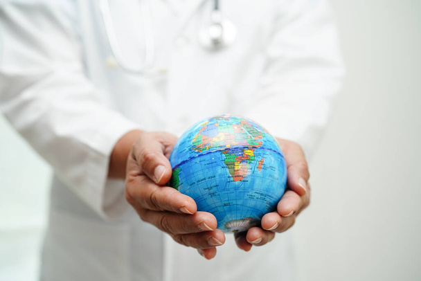 Bangkok, Thailand March 15, 2023 Asian Doctor holding globe in hand at hospital. - Foto, Bild
