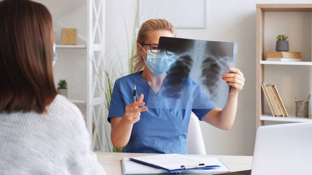 X-ray examination. Skeleton radiology. Woman doctor surgeon holding film scan radiography diagnostic in hospital bone disease treatment. - Foto, afbeelding