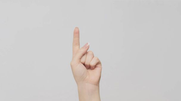 Hand gesture. One number. Woman counting pointing finger up on light gray background. - Foto, Imagem