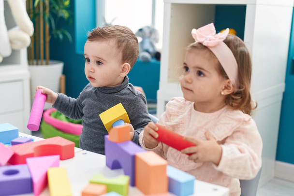 Adorable niño y niña jugando con bloques de construcción sentado en la mesa en el jardín de infantes - Foto, imagen